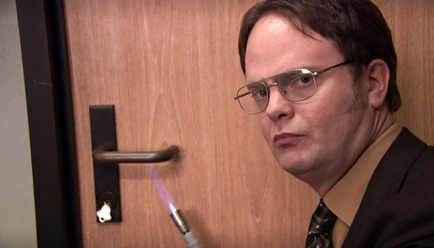 Dwight from The Office heating up a door handle with a torch